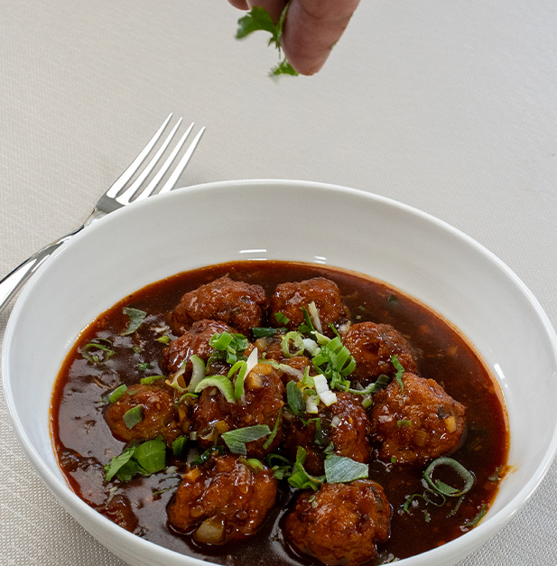 bowl of meatballs in sauce garnished with herbs and green onions fork beside dish 5 delicious recipes