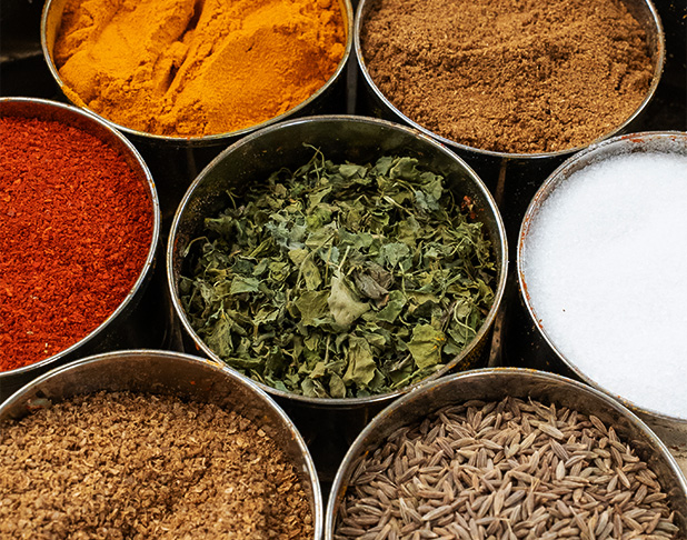 assorted spices in round metal containers including turmeric cumin red chili flakes and dried herbs suitable for cooking two essential dishes