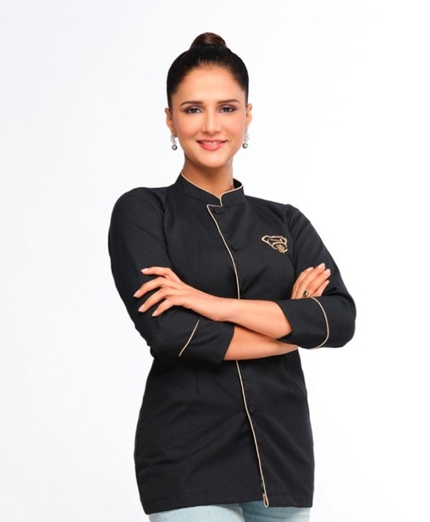 female chef wearing black uniform with arms crossed smiling in a professional setting representing culinary skills and expertise about 6 different dishes